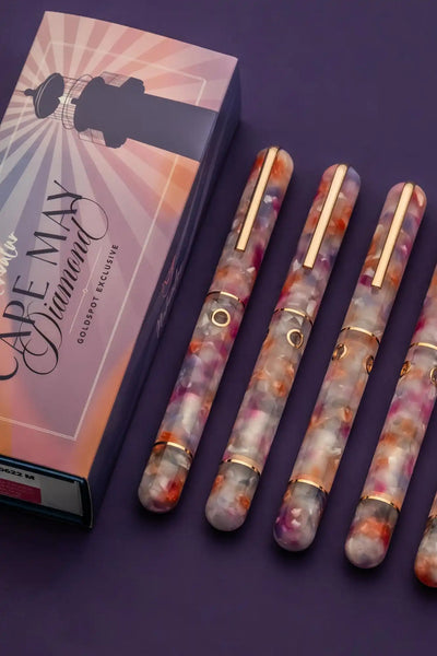 A collection of five colorful fountain pens with gold-colored accents, displayed next to their matching box.