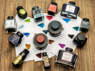 A Variety of Fountain Pen Ink Bottles and Ink Color Swatches on Paper