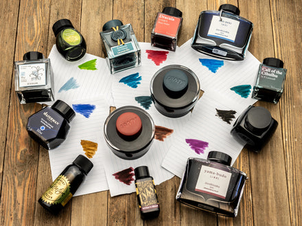 A Variety of Fountain Pen Ink Bottles and Ink Color Swatches on Paper